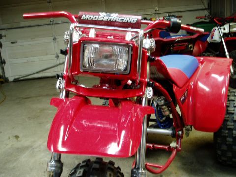 2000 Ford E350 - A red three-wheeled ATV with blue seat and Moose Racing handlebars is parked in a garage.