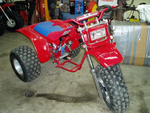 2000 Ford E350 - A red three-wheeled ATV with a blue seat and MOOSERACING handlebars is parked indoors.