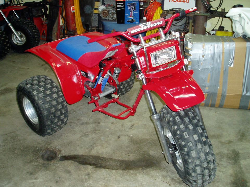 Red three-wheeled ATV with blue seat and MOOSERACING handlebars
