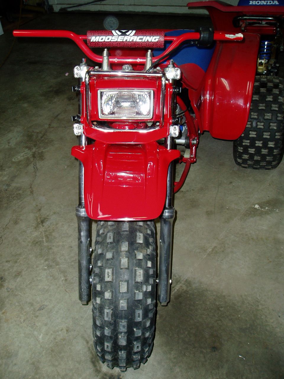 Front view of red three-wheeled ATV with Moose Racing handlebars