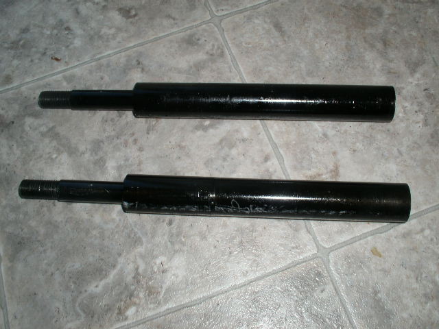 Two black painted steel tubular shafts lying on tile floor