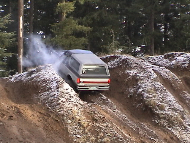 Bronco II going up a dirt hill with smoke coming from the side