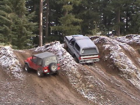 1994 Ford Explorer - Two off-road vehicles navigate a snowy, muddy incline during an outdoor event.