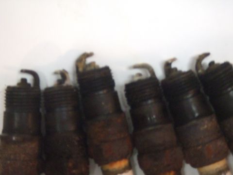 1996 Ford Bronco - A row of used spark plugs shows signs of wear and tear.