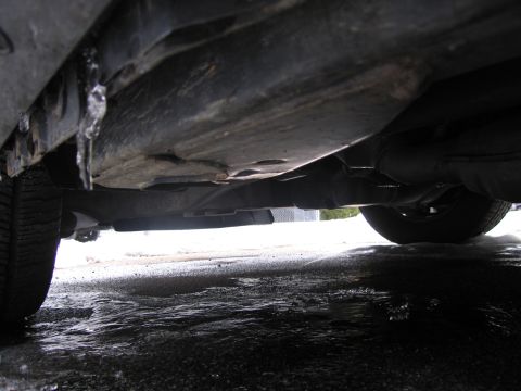 1991 Ford LTD Crown Victoria - A low-angle view of a vehicle's undercarriage reveals icicles and a wet, icy surface below.