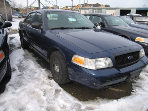 1991 Ford LTD Crown Victoria - Front view of a dark blue Ford Crown Victoria, parked in a snowy lot next to another vehicle.