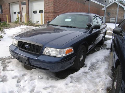 1991 Ford LTD Crown Victoria - A dark blue Ford Crown Victoria Police Interceptor sits parked in a snowy lot next to another vehicle.