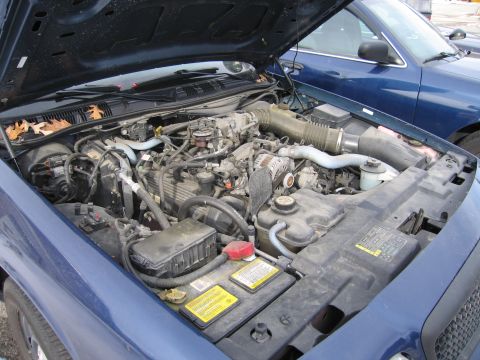 1991 Ford LTD Crown Victoria - Engine bay of a 1991 Ford Crown Victoria LTD, with another blue vehicle visible in the background.