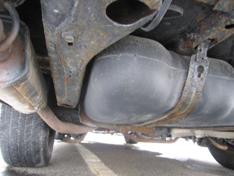 1991 Ford LTD Crown Victoria - The undercarriage of a vehicle, revealing the fuel tank and exhaust system, with visible signs of wear and tear.