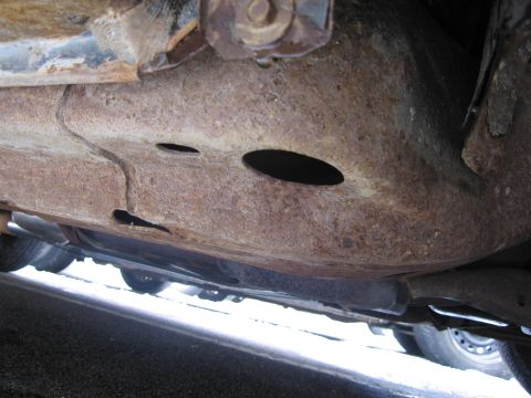 1991 Ford LTD Crown Victoria - The underside of a vehicle frame shows significant rust and damage, with several holes visible.