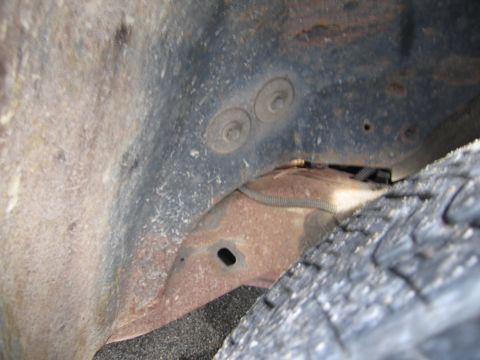1991 Ford LTD Crown Victoria - Close-up view of a rusty vehicle frame and tire tread, showing signs of wear and tear.