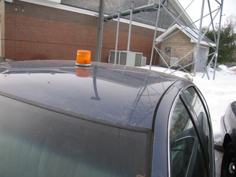 1991 Ford LTD Crown Victoria - Car roof with an amber warning light, set against a brick building and metal structure.