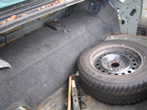 1991 Ford LTD Crown Victoria - The interior of a car trunk is shown, containing a spare tire and a jack.