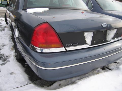 1991 Ford LTD Crown Victoria - The rear of a blue Ford Crown Victoria is shown with snow on the trunk and a second vehicle parked closely behind it.