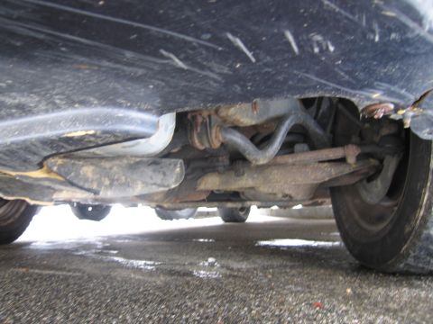 1991 Ford LTD Crown Victoria - The undercarriage of a vehicle is visible, revealing suspension parts and a worn tire.