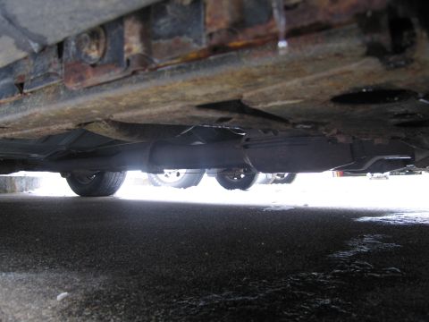 1991 Ford LTD Crown Victoria - The underside of a car reveals significant rust on the frame and exhaust components.