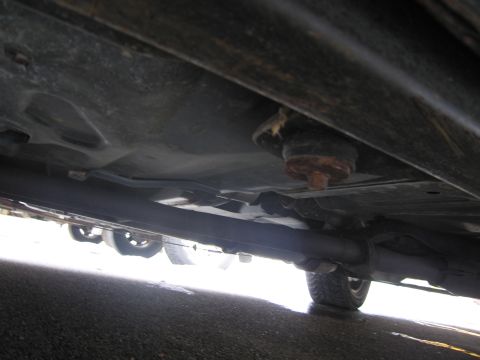1991 Ford LTD Crown Victoria - A low-angle shot reveals the underside of a vehicle, focusing on the exhaust system and suspension parts.