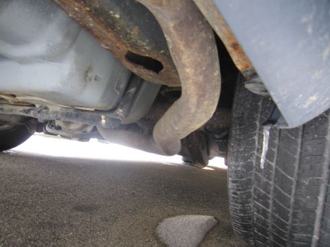 1991 Ford LTD Crown Victoria - Close-up of a car's undercarriage, focusing on the exhaust system and rear tire.