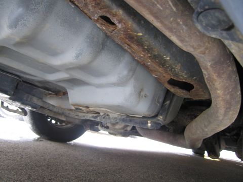 1991 Ford LTD Crown Victoria - The undercarriage of a vehicle displays significant rust on the frame and exhaust system components.