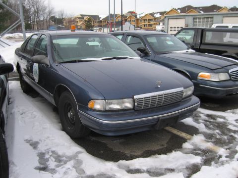 1991 Ford LTD Crown Victoria - This dark blue sedan, possibly a 1991 model, is parked in a snowy lot with an orange light on its roof.
