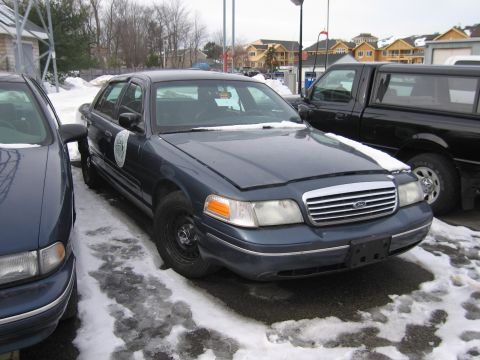 1991 Ford LTD Crown Victoria - A Ford Crown Victoria Police Interceptor sits in the snow next to a black pickup truck.
