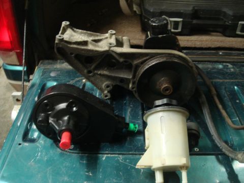 1996 Ford Bronco - Power steering pump and reservoir components are laid out on a teal surface.