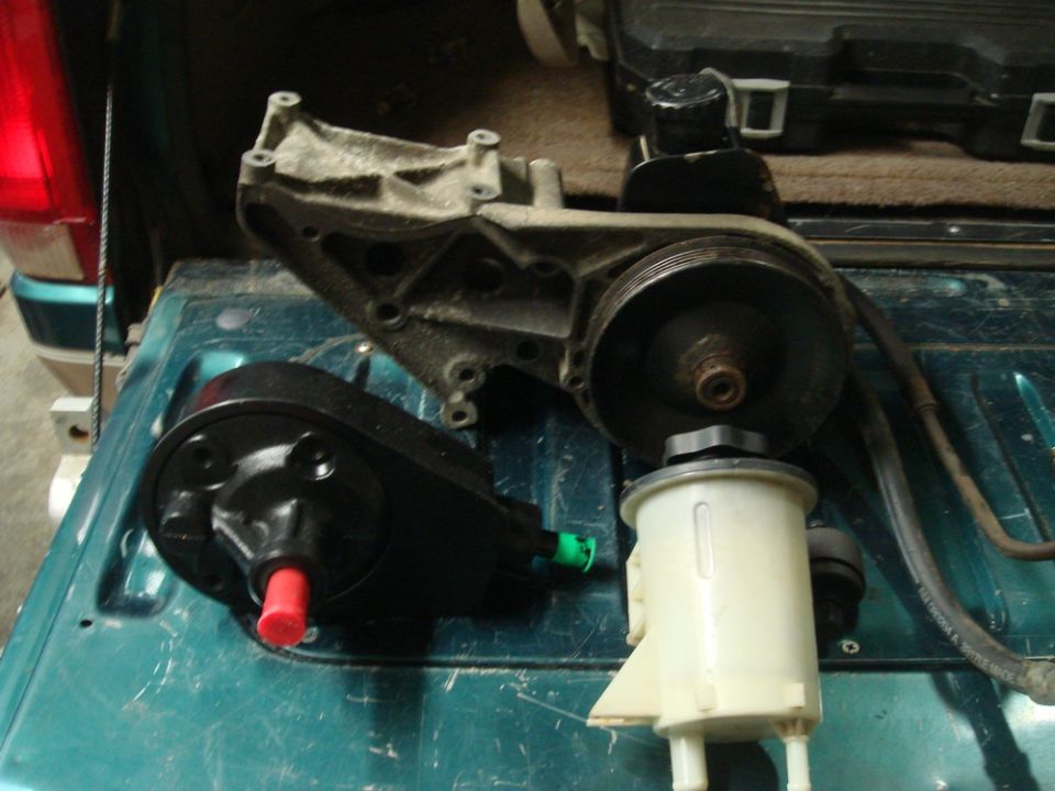 Power steering pump, reservoir, and bracket on a teal surface