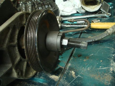 1996 Ford Bronco - A pulley removal tool is attached to a pulley, with a hydraulic hose nearby. Tools are visible in the background.