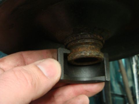 1996 Ford Bronco - A hand holds a metal part near a rusty component, likely from a vehicle's engine or suspension system.