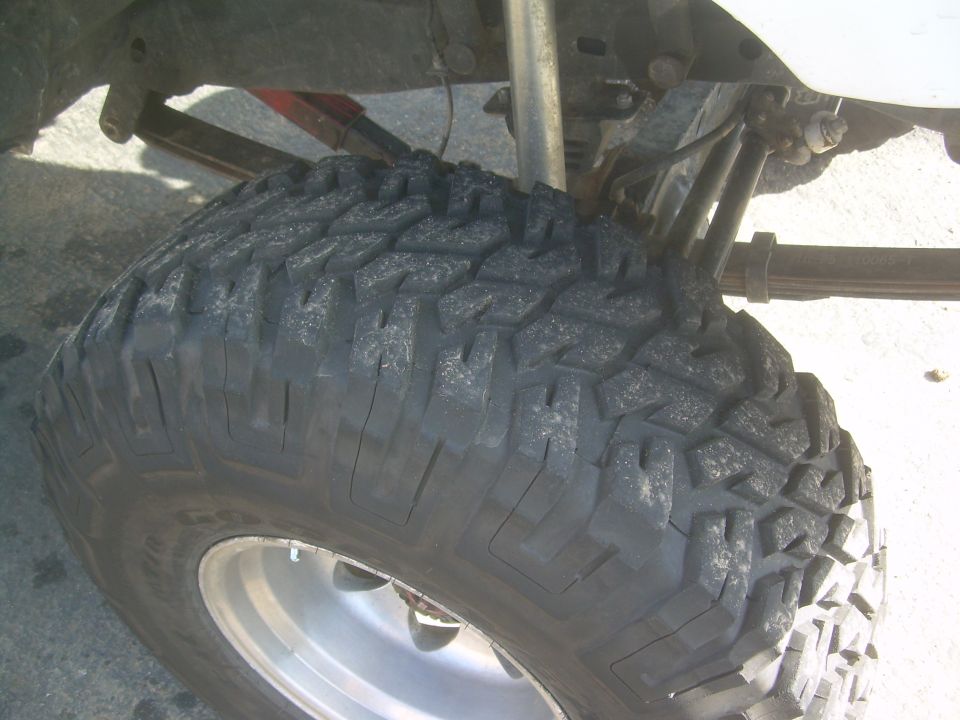 Off-road tire on a vehicle's suspension, showing leaf springs and a shock absorber
