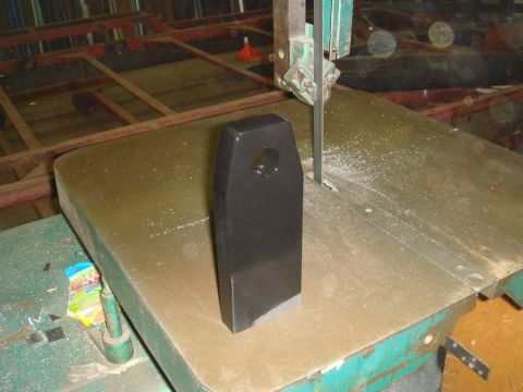 1996 Ford Bronco - A black metal part is being cut by a band saw in a workshop.
