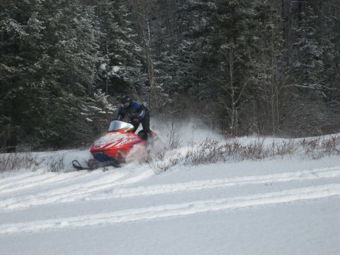 1995 Ford Bronco - A snowmobile kicks up snow as it travels across a winter landscape.