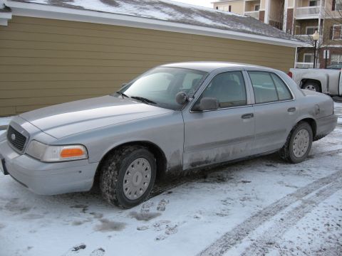 2004 Ford Crown Victoria - A silver 2004 Ford Crown Victoria sedan is parked in the snow, showing its front three-quarter view.