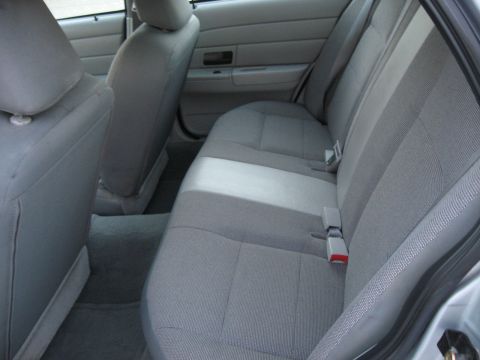 2004 Ford Crown Victoria - The interior of the vehicle shows the rear seats and door panel with gray fabric upholstery.