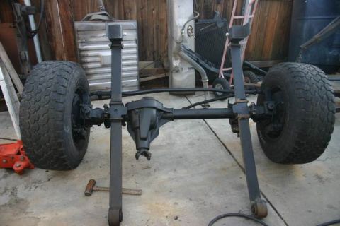 1991 Ford Bronco - This image shows a vehicle's front axle assembly, including leaf springs and tires, in a workshop setting.