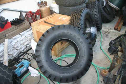 1991 Ford Bronco - Various tires and automotive parts are piled up in a workshop or storage area.