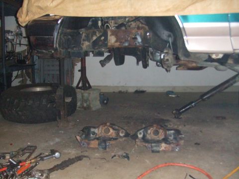 1996 Ford Bronco - The vehicle's undercarriage is exposed, with suspension components laid out on the garage floor.