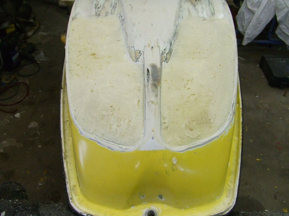 Yellow PWC hull stripped to bare foam and fiberglass at rear footwells during repair