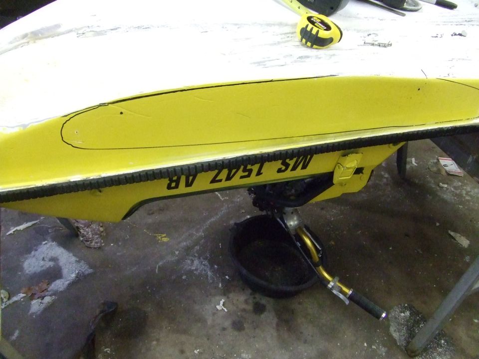 Yellow personal watercraft turned upside down on sawhorses in a garage for hull work
