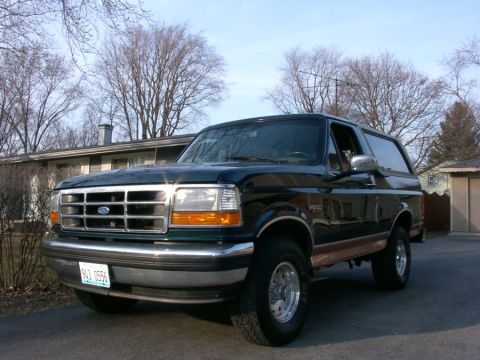 1994 Ford Bronco - A dark green 1994 Ford Bronco is shown from the front-left in a residential setting.