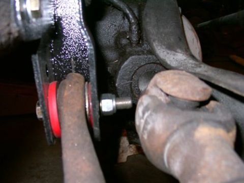 1994 Ford Bronco - Close-up of suspension components with red polyurethane bushings and rusty metal parts.