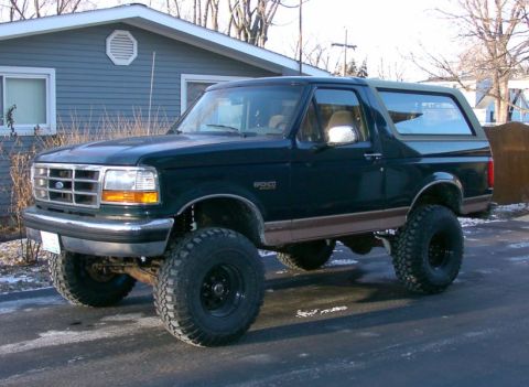 1994 Ford Bronco - This lifted Ford Bronco has a dark green body with brown trim and large off-road tires.