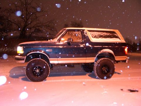1994 Ford Bronco - A lifted 1994 Ford Bronco is seen from the side during a snowfall at night.