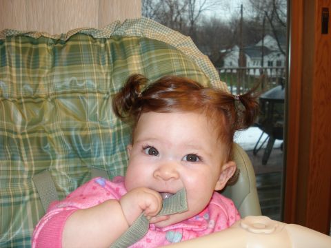 2000 Ford Crown Victoria - A baby sits in a high chair, chewing on a strap while looking at the camera.