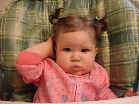 2000 Ford Crown Victoria - A baby with pigtails and a pink outfit sits in a high chair, looking at the camera.