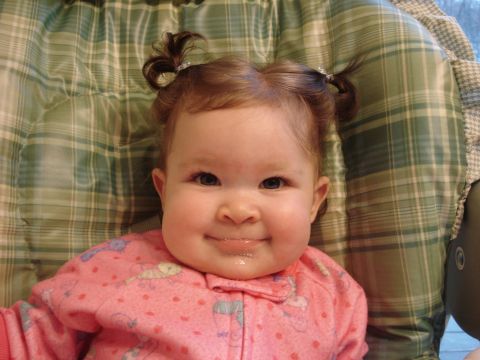 2000 Ford Crown Victoria - Baby in pink pajamas with pigtails smiles, sitting against a green plaid background.