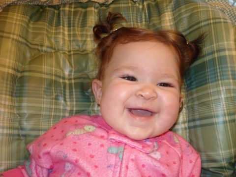 2000 Ford Crown Victoria - A happy baby girl with red hair and pigtails is lying down on a green plaid surface.