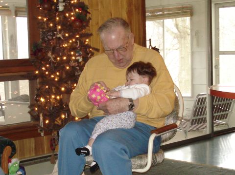 2000 Ford Crown Victoria - A man holds a baby while sitting near a decorated Christmas tree.