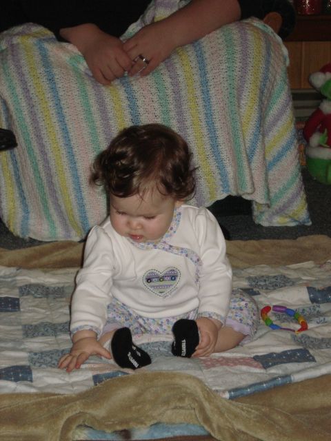 2000 Ford Crown Victoria - A baby sits on a quilt, looking down at their hands. A colorful toy rests to the side.