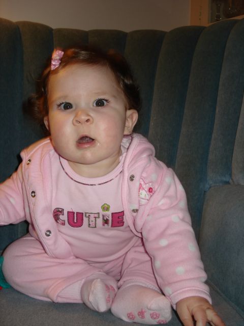2000 Ford Crown Victoria - A baby girl wearing a pink outfit with 'CUTIE' written on it sits on a couch.